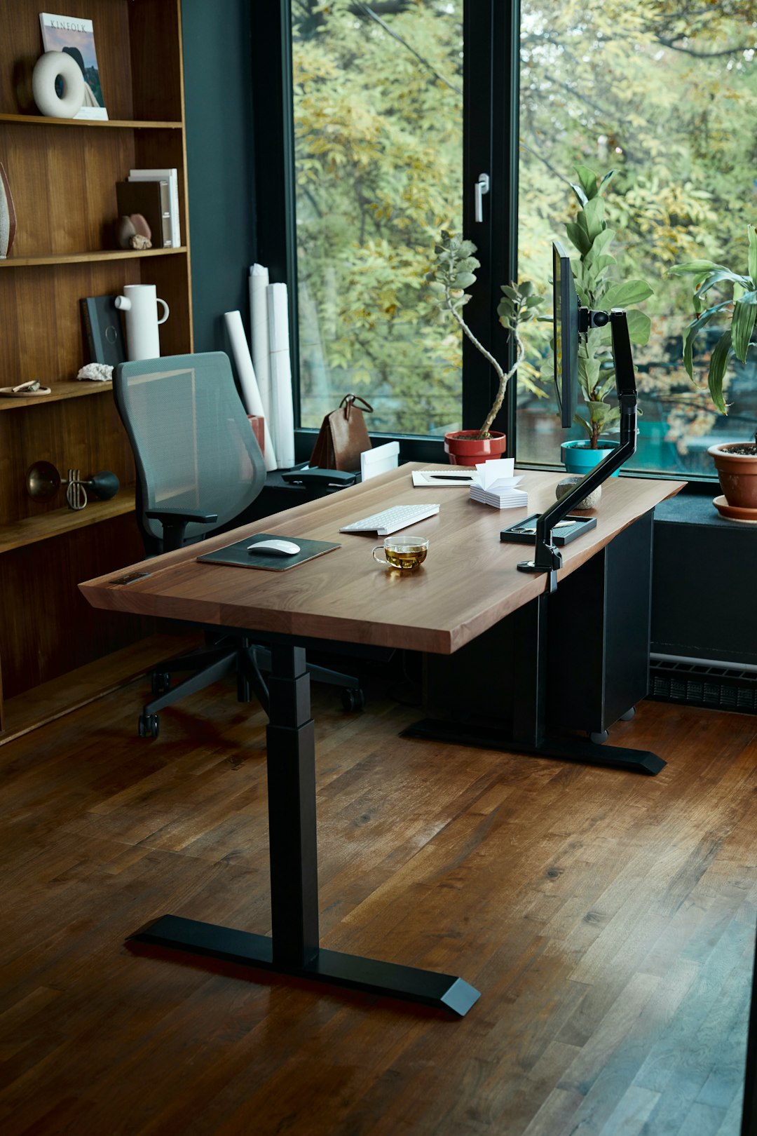 A wooden standing desk with a computer monitor and keyboard in a home office